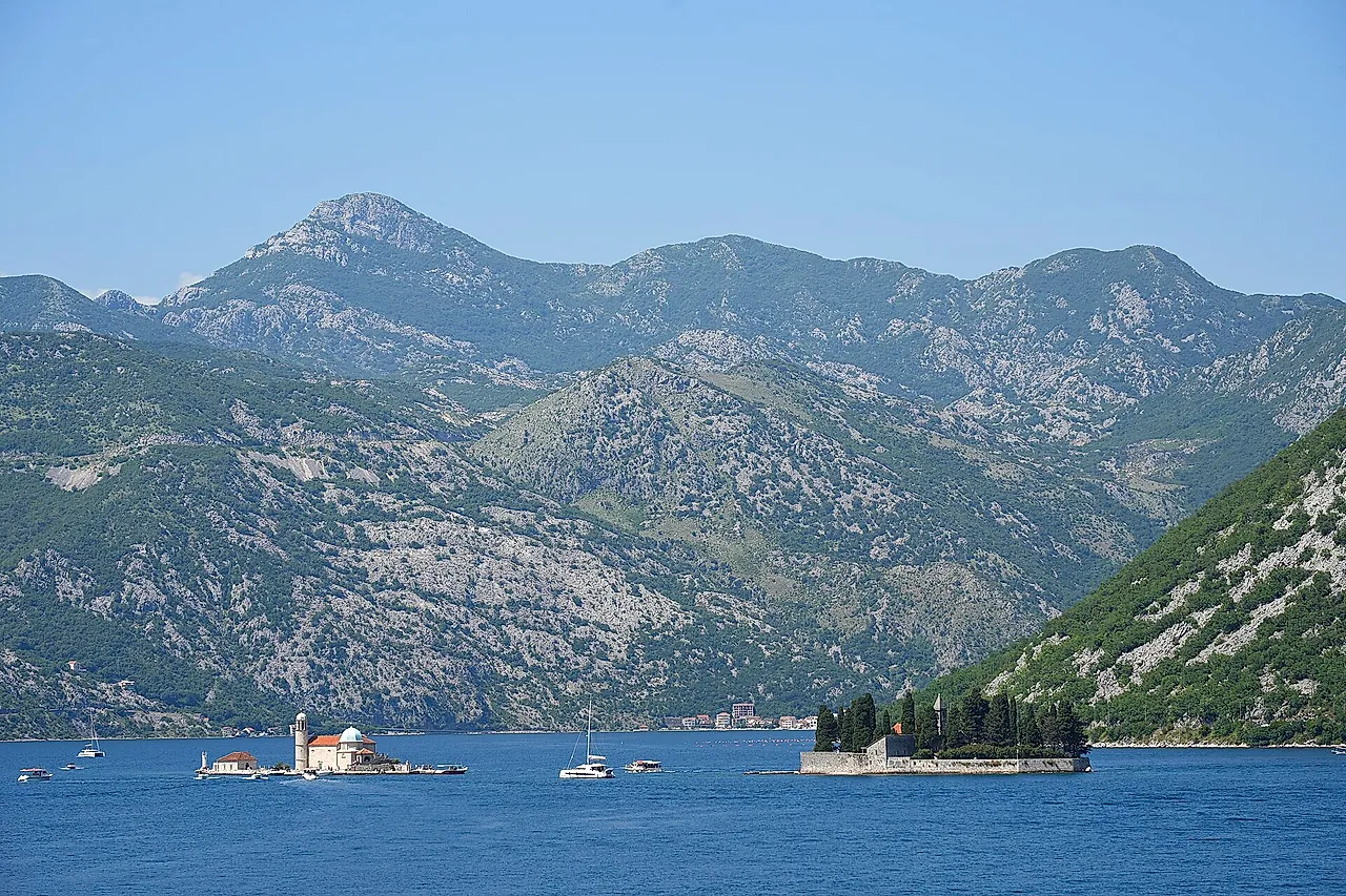 The Bay of Kotor near Perast, with the two islets in the distance and mountains under a blue sky