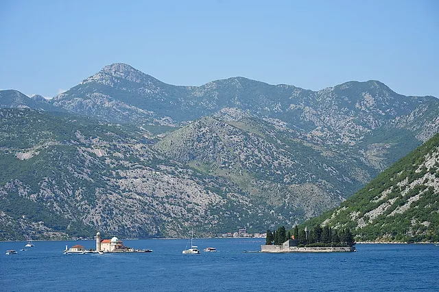 The Bay of Kotor near Perast, with the two islets in the distance and mountains under a blue sky