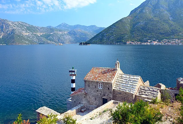 The Bay of Kotor from the road at Lepetane: a small stone church with a striped lighthouse, Perast in the distance and mountains