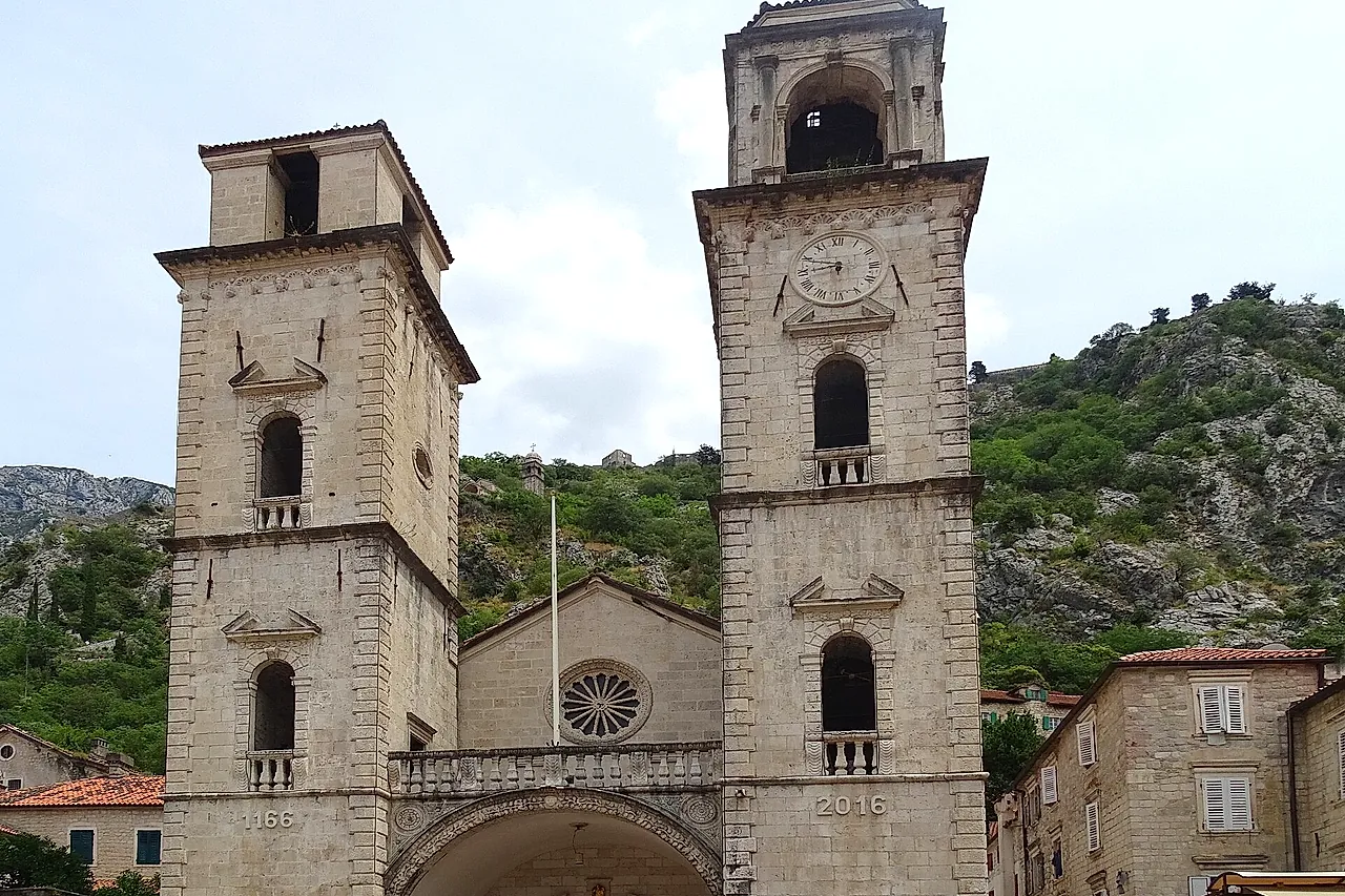 The twin bell towers and façade of the Cathedral of St Tryphon in Kotor, with the mountain slope behind